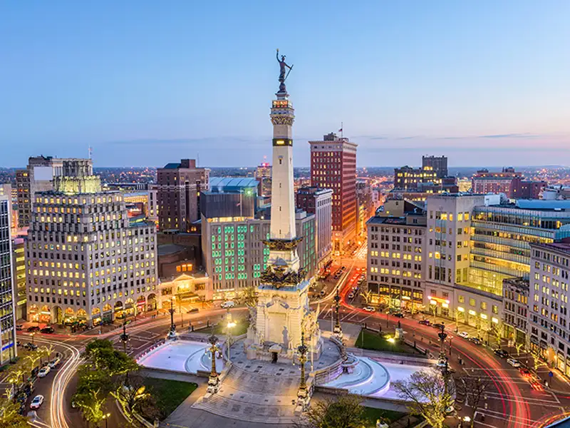 Monument Circle with the Soldiers and Sailors Monument surrounded by city buildings at dusk.